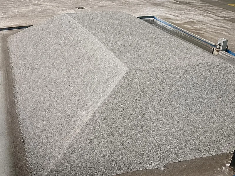 Light-colored stockpile with a granular surface inside a storage facility