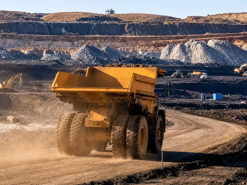 Haul truck raising dust on an unpaved road in an open-pit mine