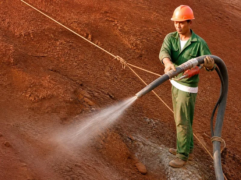 Worker spraying liquid onto an exposed soil slope