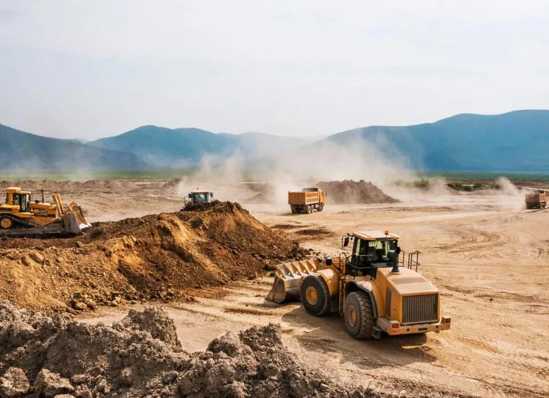 Wheel loader, bulldozer and haul trucks at a dusty earthworks site