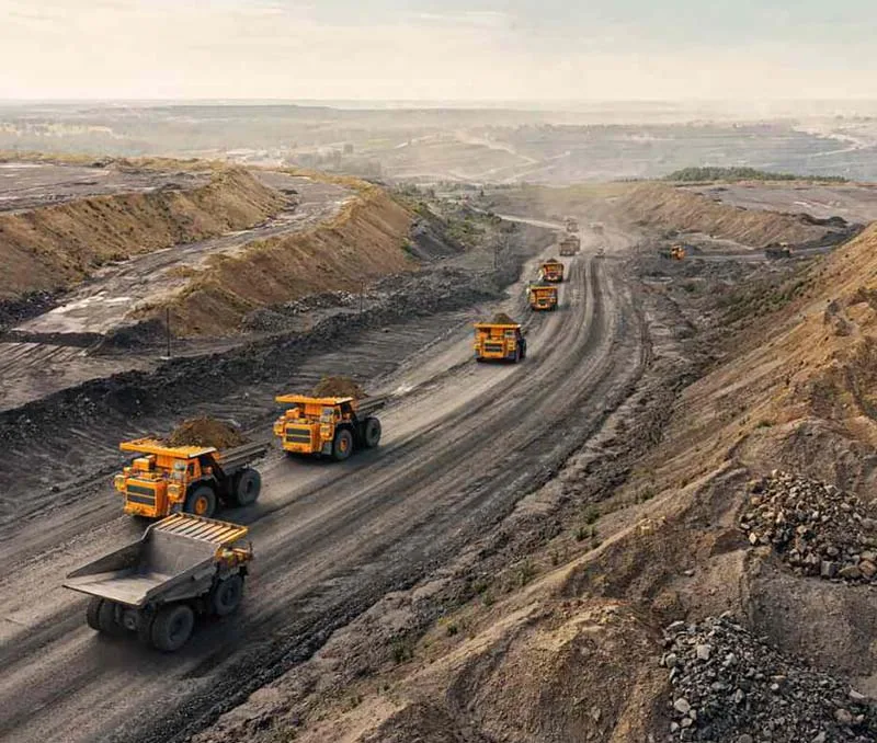 Haul trucks traveling on an unpaved road in an open-pit mine